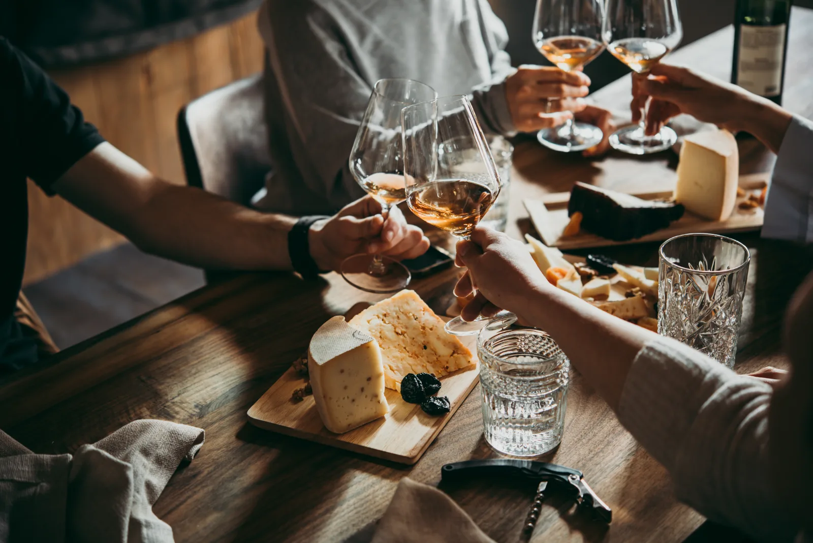 Amis trinquant à l'apéritif autour d'une planche de fromages et d'un verre de vin