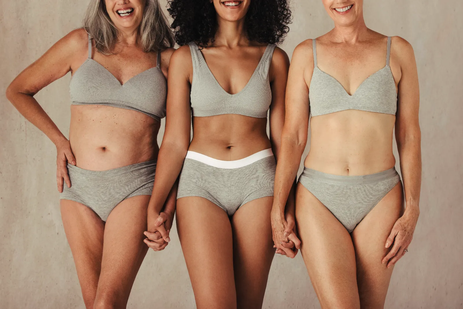 Trois femmes d'âges et de morphologies différentes se tenant la main, illustrant le lien entre stress, cortisol et poids abdominal